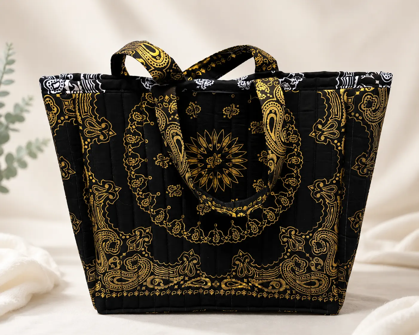 Black quilted tote bag featuring a metallic-gold bandana-inspired pattern and coordinating fabric handles